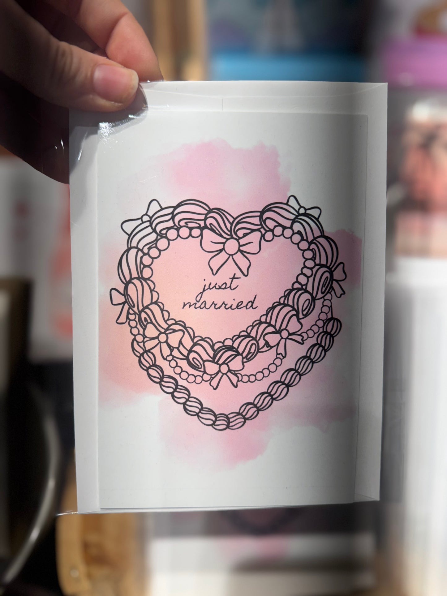 White product packaging with 'just married' design on a pink watercolor background