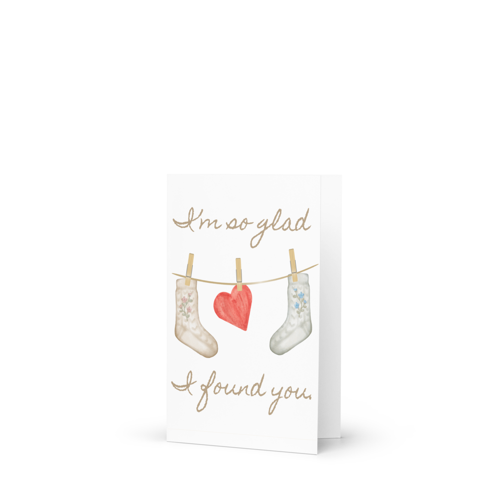 Greeting card with stockings and a heart on a clothesline, text 'I'm so glad I found you.'