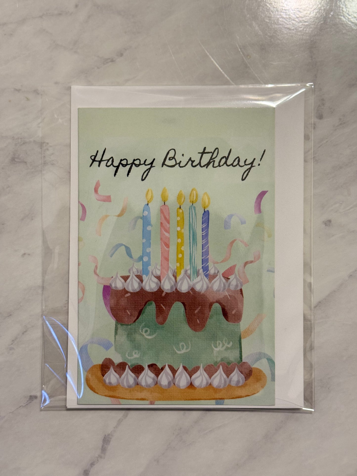Birthday card with a cake illustration and 'Happy Birthday!' text on a marble surface.