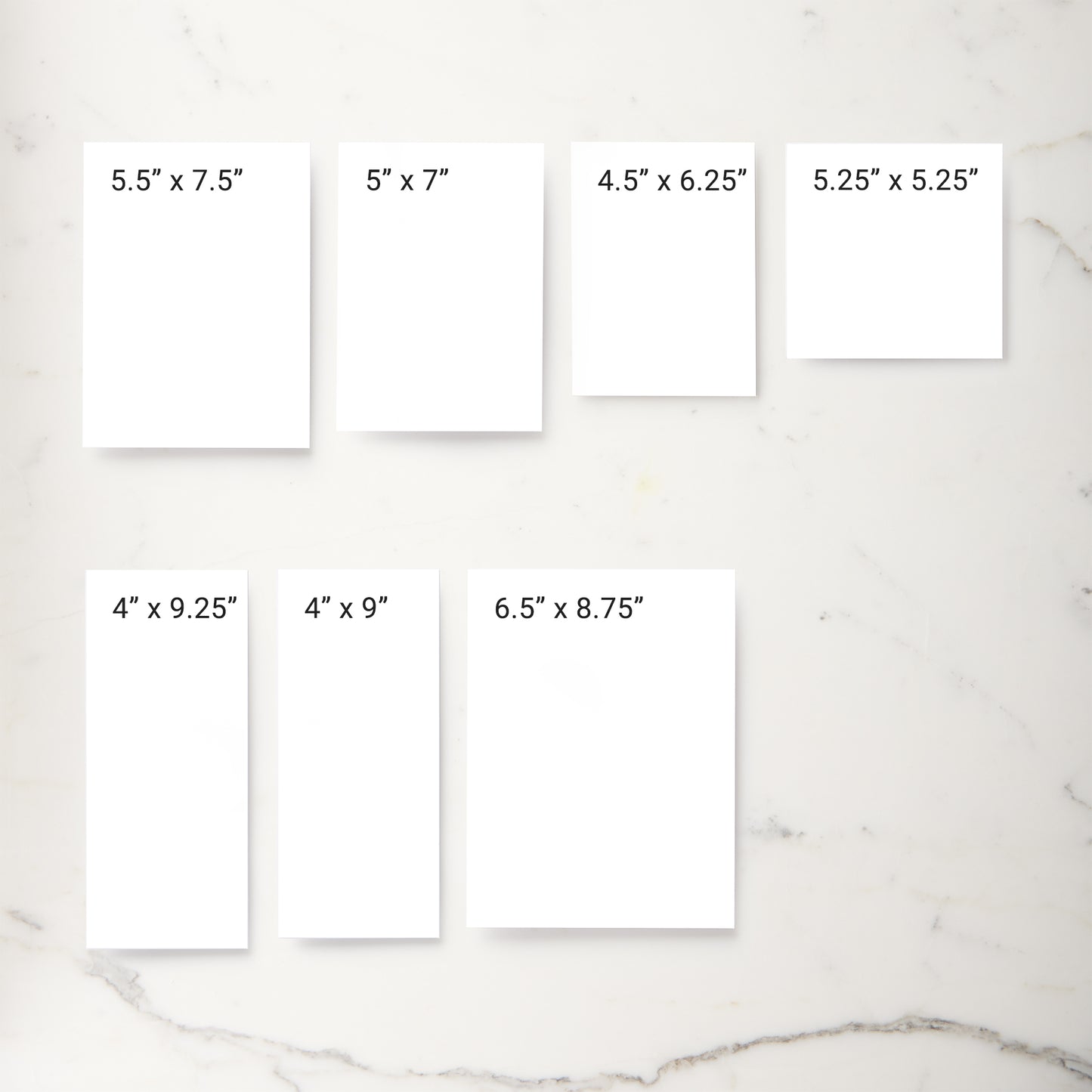 Six white rectangular print mockups arranged on a light marble surface, each labeled with different print dimensions such as 5.5" x 7.