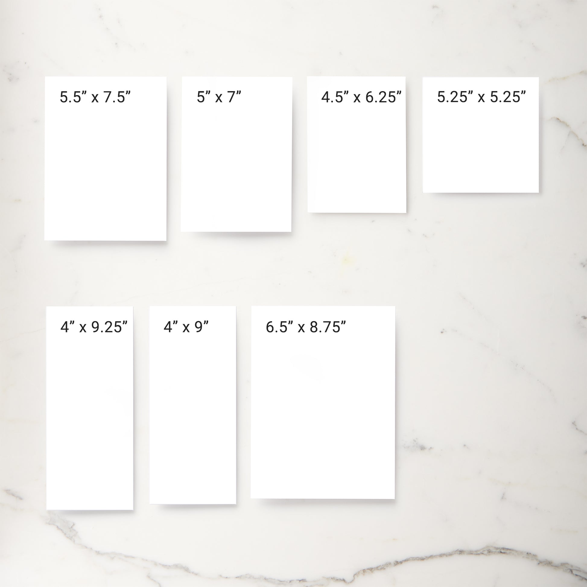 Six white rectangular print mockups arranged on a light marble surface, each labeled with different print dimensions such as 5.5" x 7.