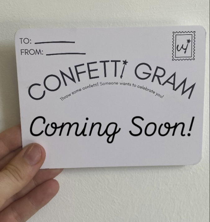 Card with 'CONFETTI GRAM Coming Soon!' text held by a hand against a white background