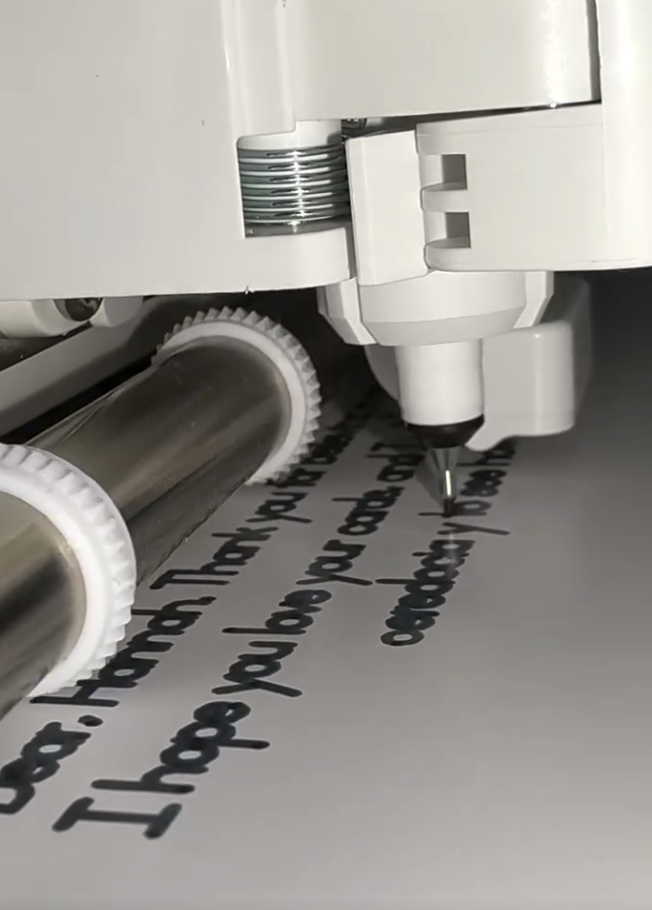 CNC Cricut machine writing text on a postcard
