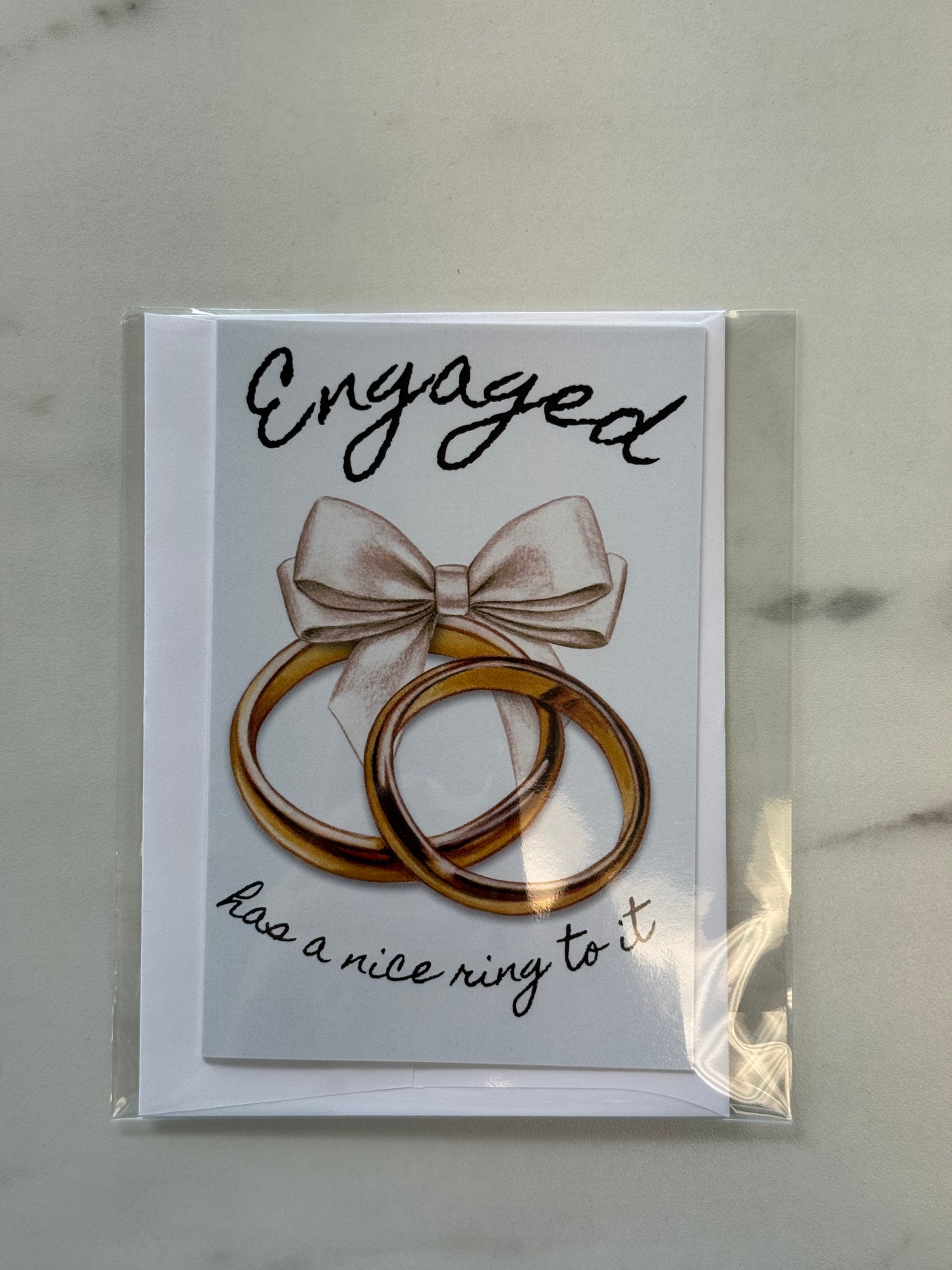 Card with rings and bow illustration on a marble surface