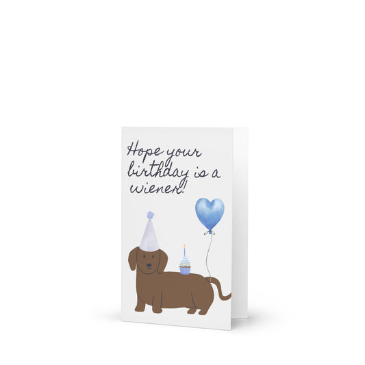 Birthday card with a dachshund, party hat, and blue balloon on a white background