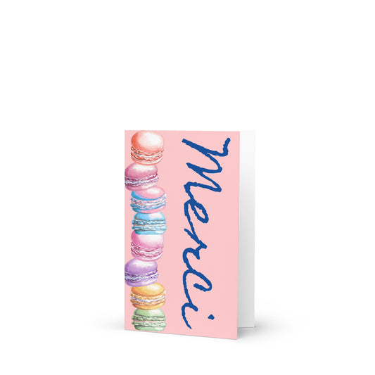 Greeting card with colorful macarons and 'Merci' text on a pink background