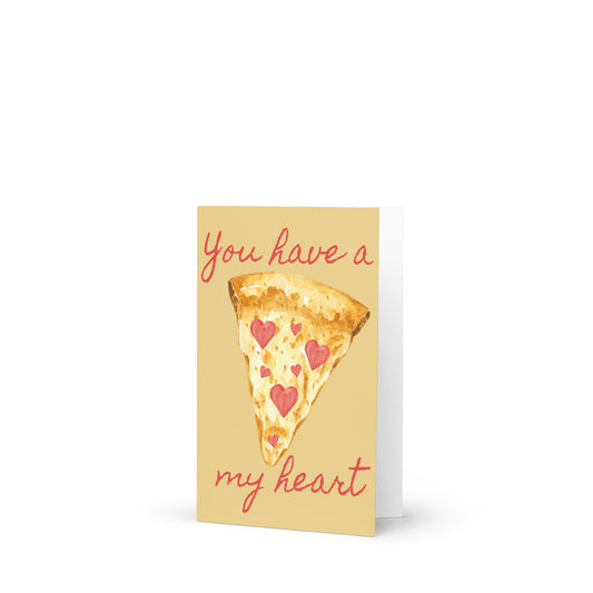 Greeting card with a slice of pizza and 'You have a (pizza) my heart' text on a white background