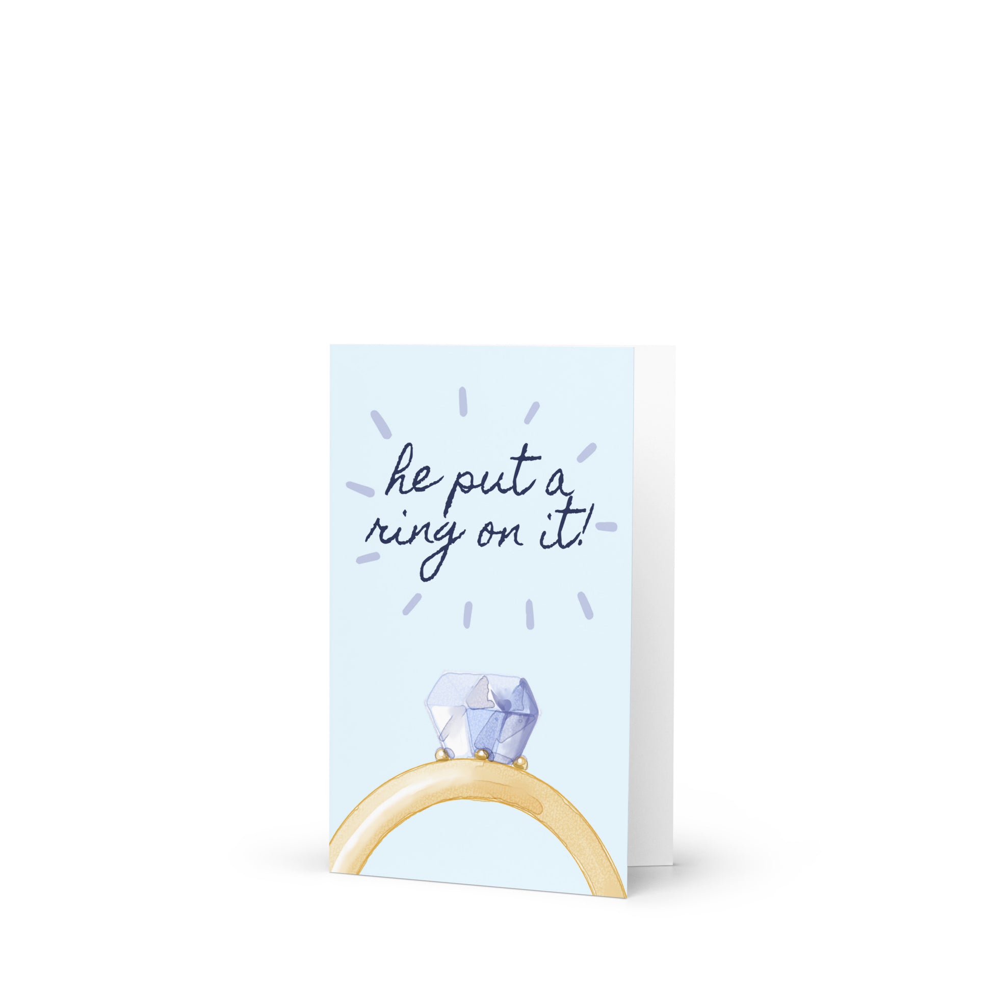 Greeting card with a ring holder and 'he put a ring on it!' text on a light blue background
