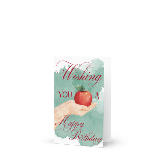 Greeting card with a hand holding an apple and 'Wishing you a Happy Birthday' text on a light blue background.