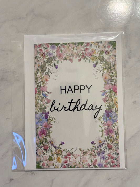 Greeting card with floral border and 'Happy Birthday' text on a marble surface