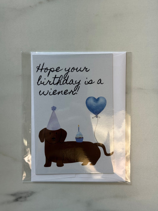 Birthday card with dachshund illustration and humorous text on a marble surface