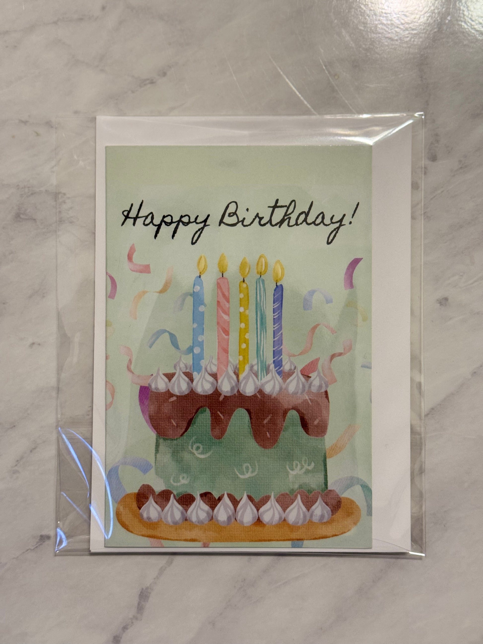 Birthday card with a cake illustration and 'Happy Birthday!' text on a marble surface.