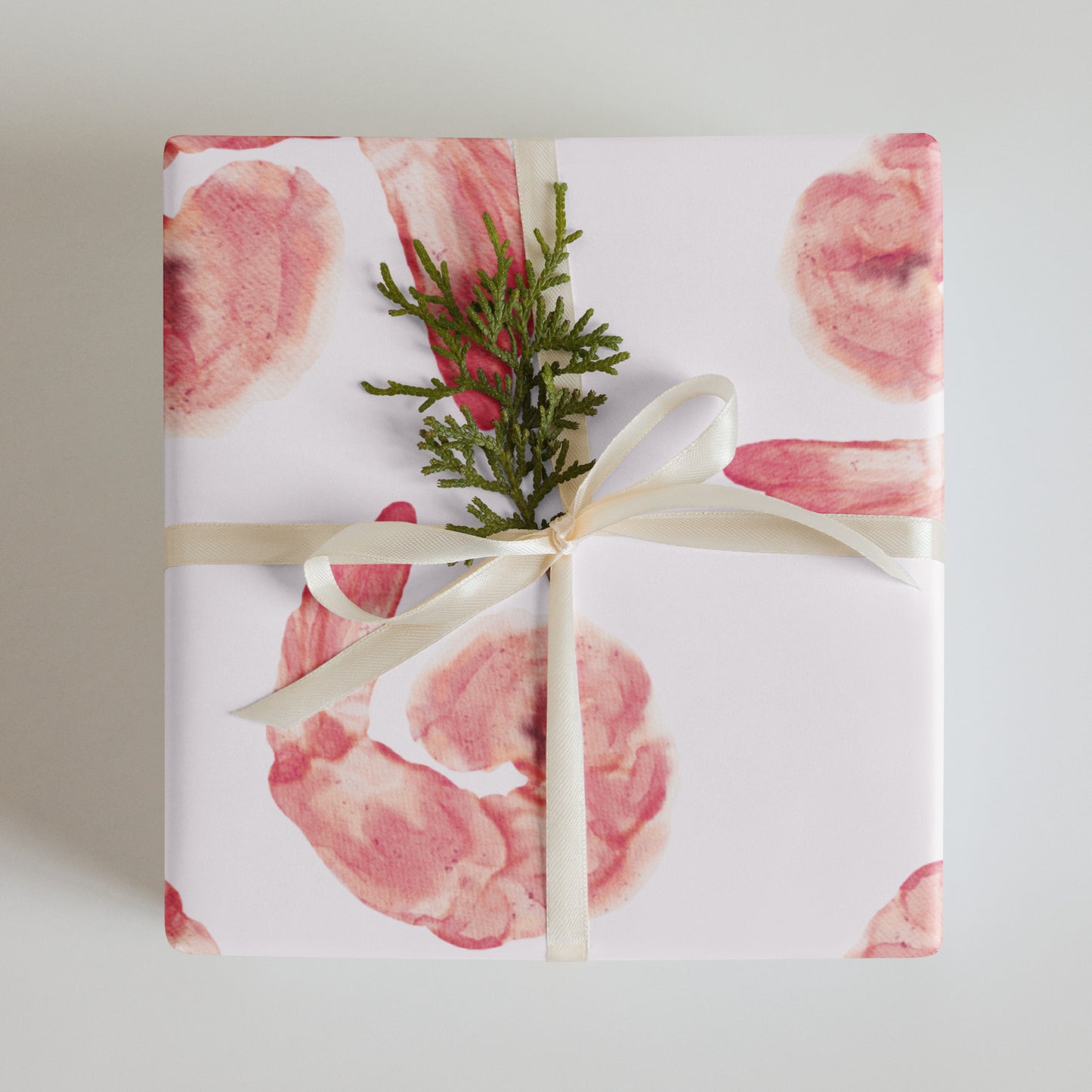 Gift wrapped in paper with pink shrimp pattern and greenery on top