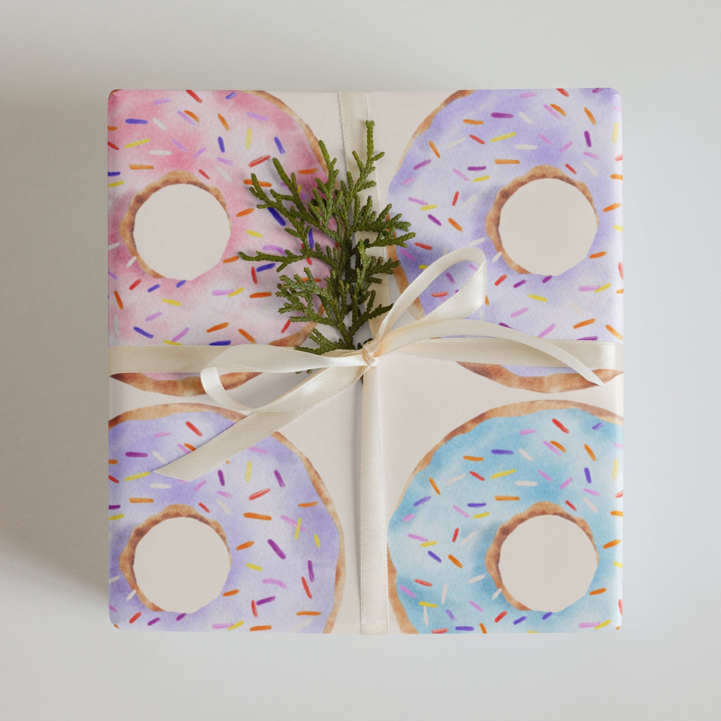 Gift wrapped in colorful donut-patterned paper with a white ribbon on a light gray background