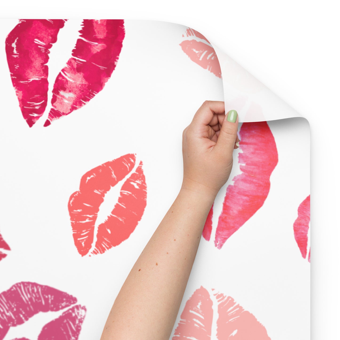 Hand holding a sheet of paper with pink lipstick kiss prints on a white background