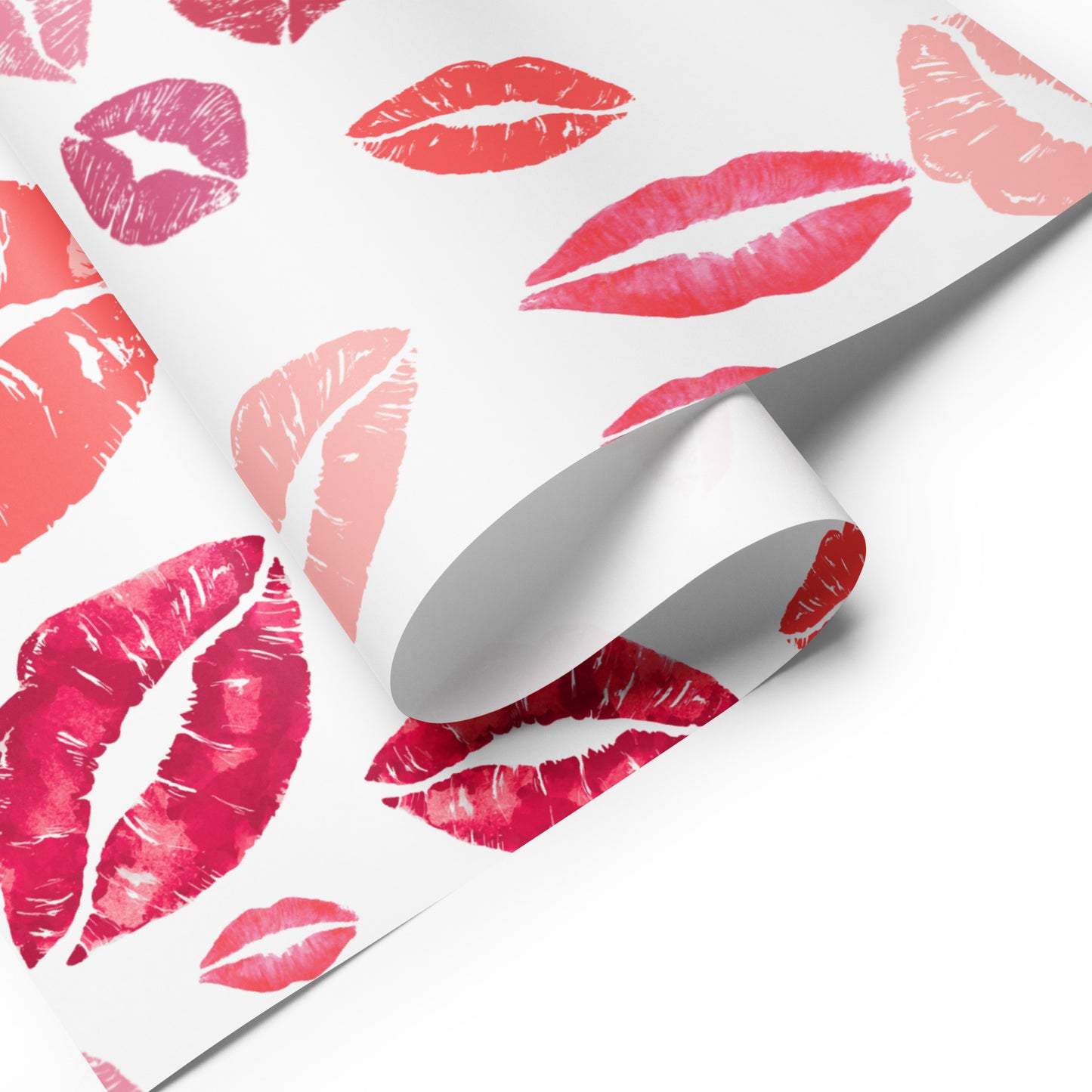 Roll of wrapping paper with pink and red lip print pattern on a white background