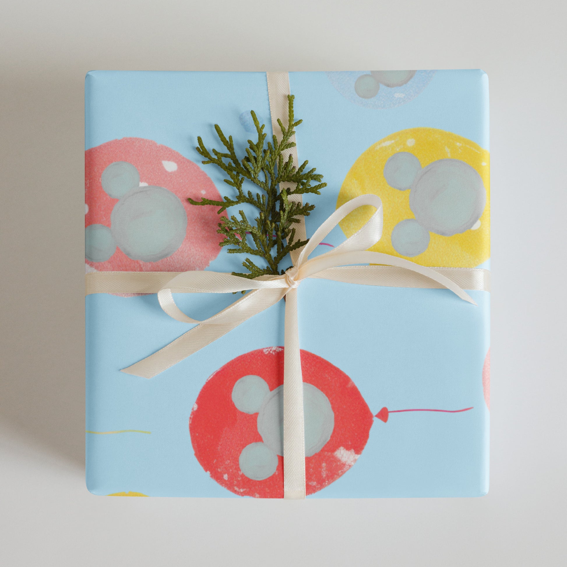 Gift wrapped in blue paper with colorful balloon designs and a white ribbon.