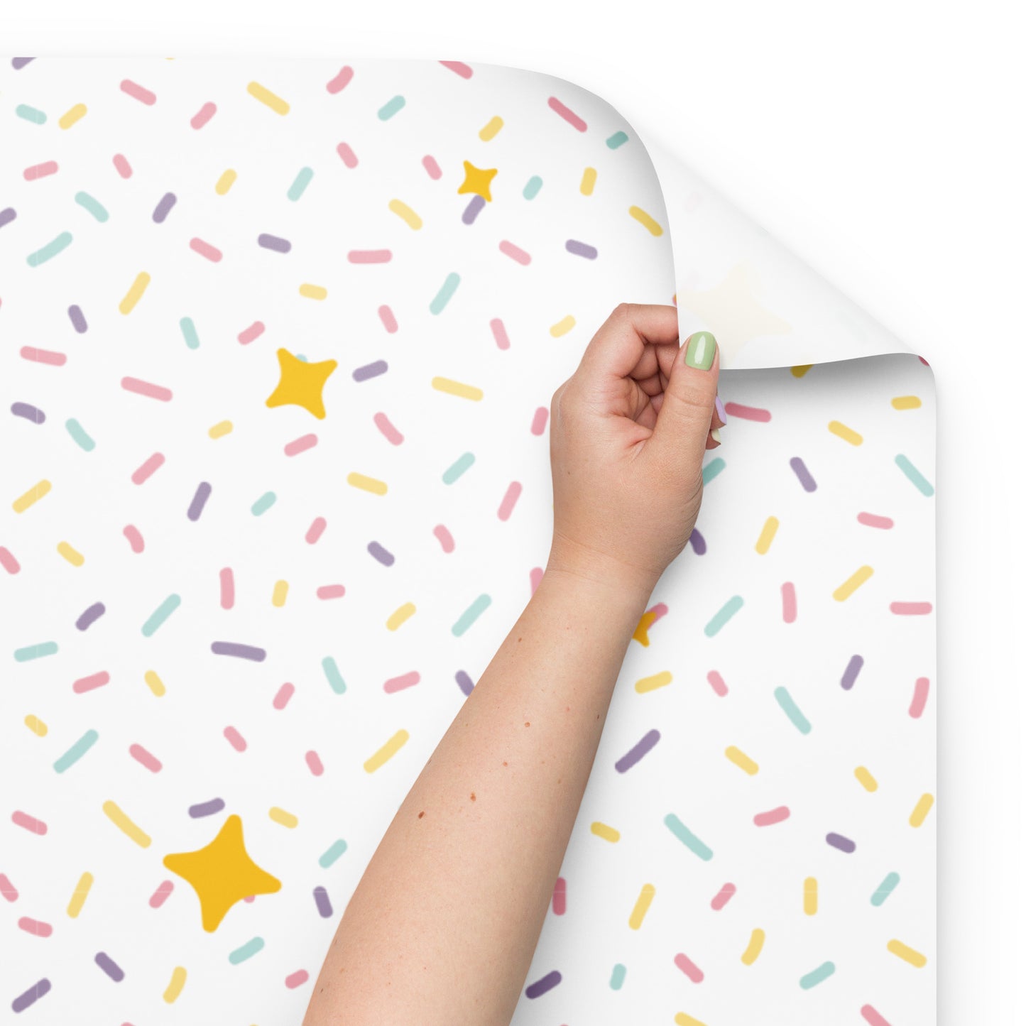 Hand holding a roll of paper with colorful sprinkles and stars pattern